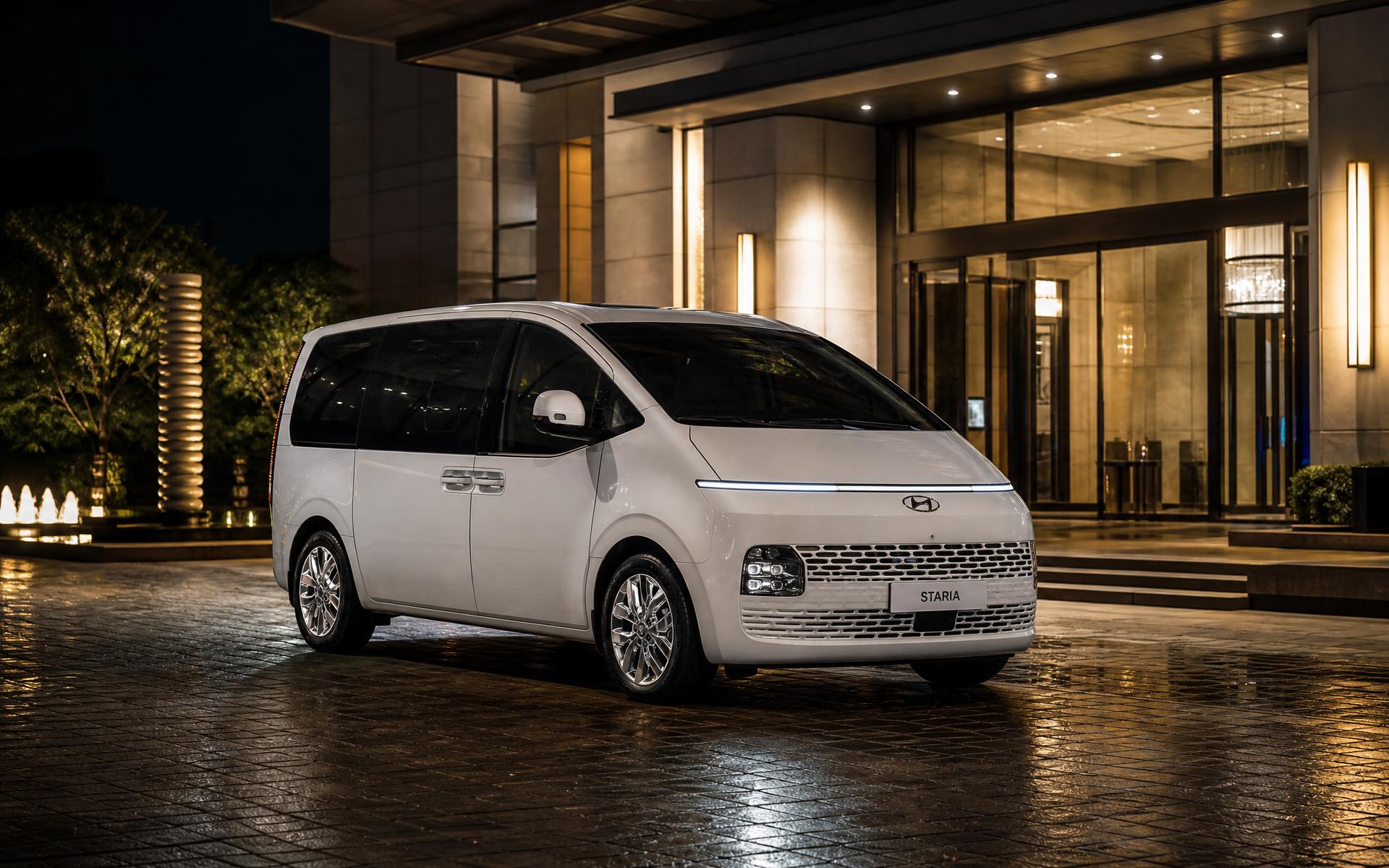 White Hyundai Staria executive van at a luxury hotel entrance at night